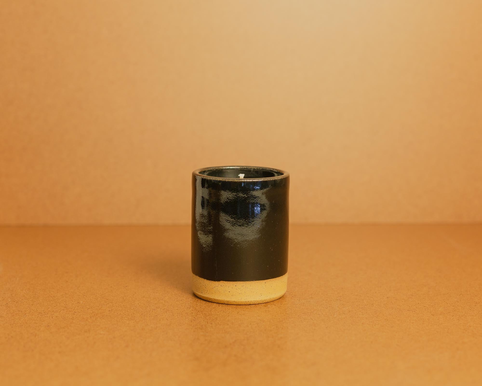 Black ceramic candle on a brown background
