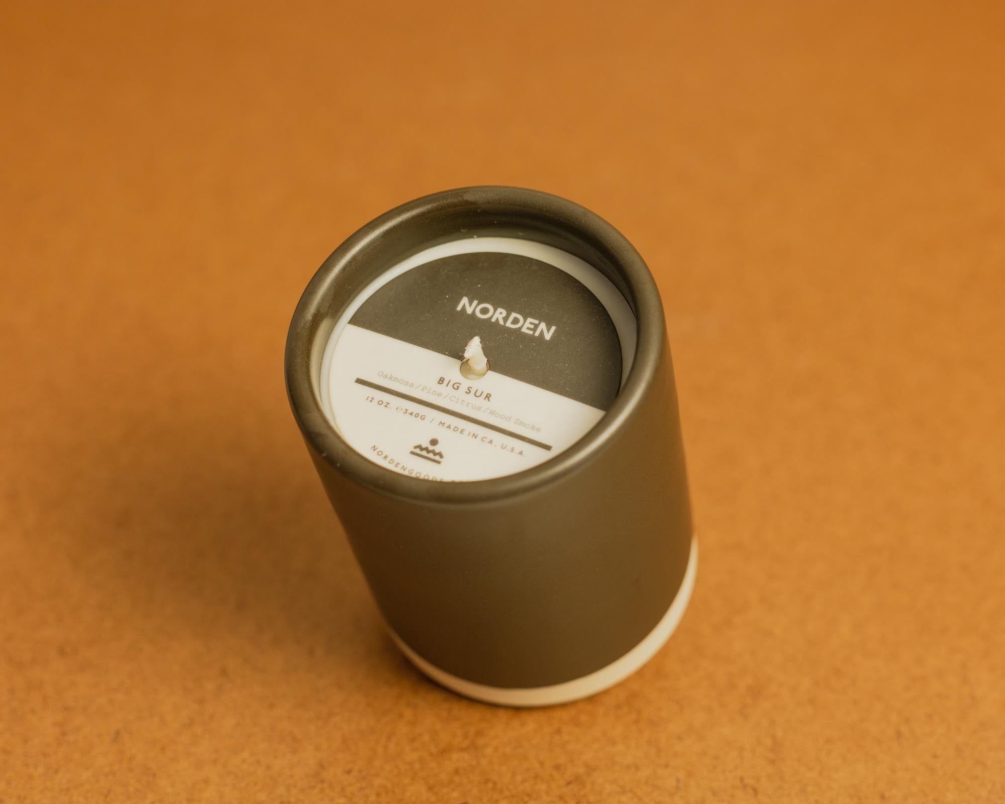 Brown ceramic candle with label on a brown background