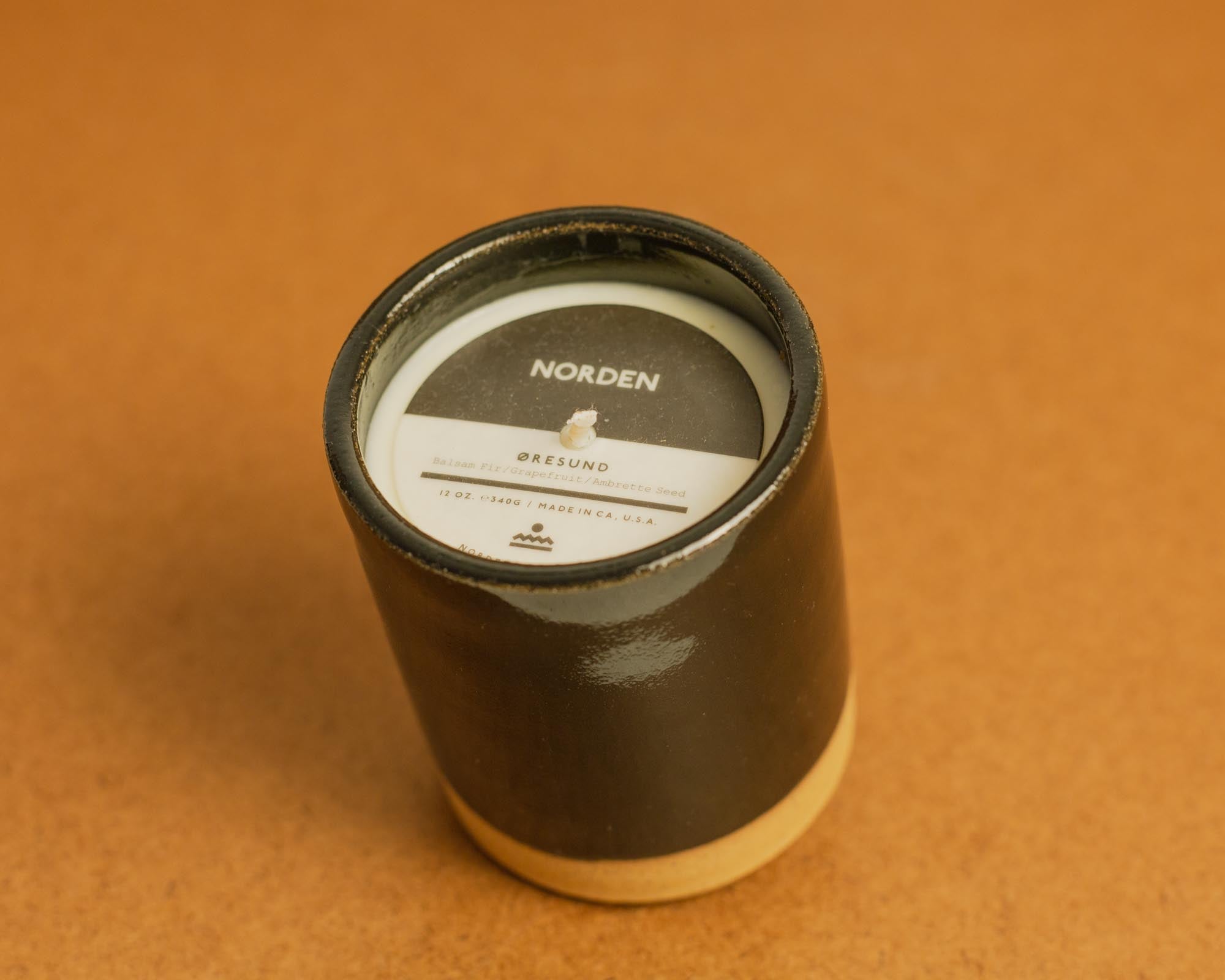 Candle in a black ceramic with a label on a brown background