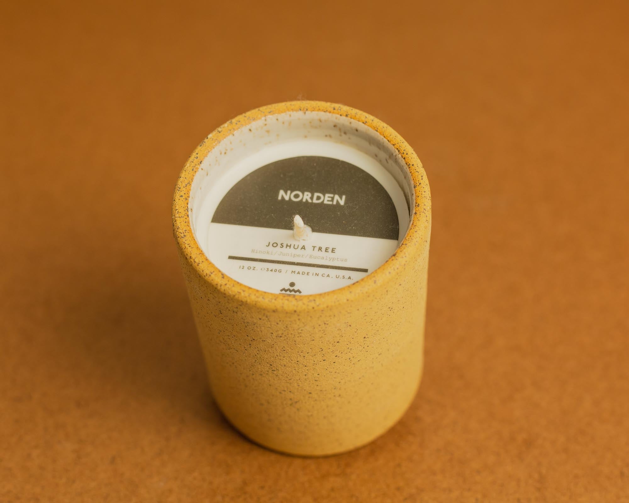 Natural clay candle with a label inside on a brown background