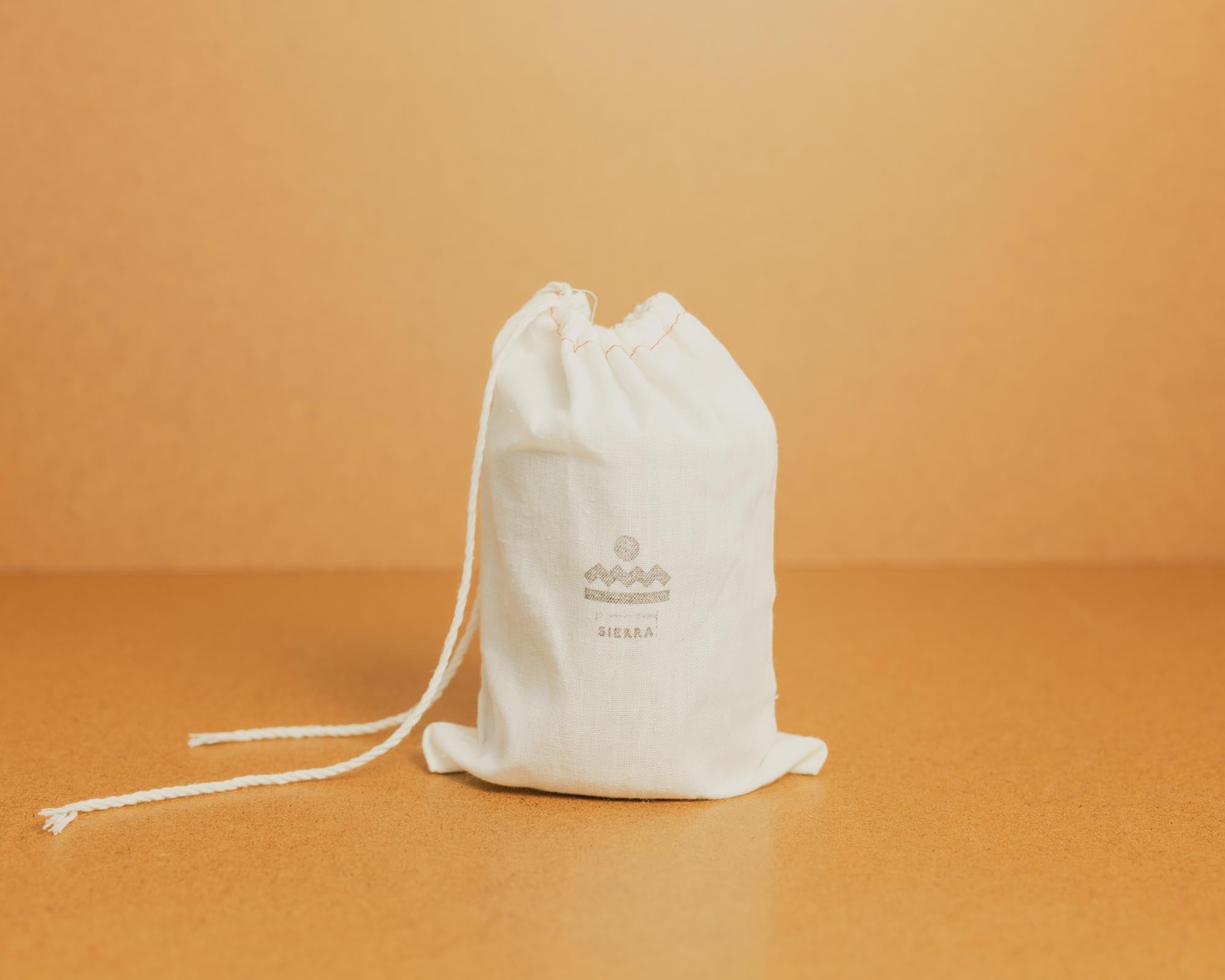 White drawstring bag with Norden branding on a brown background