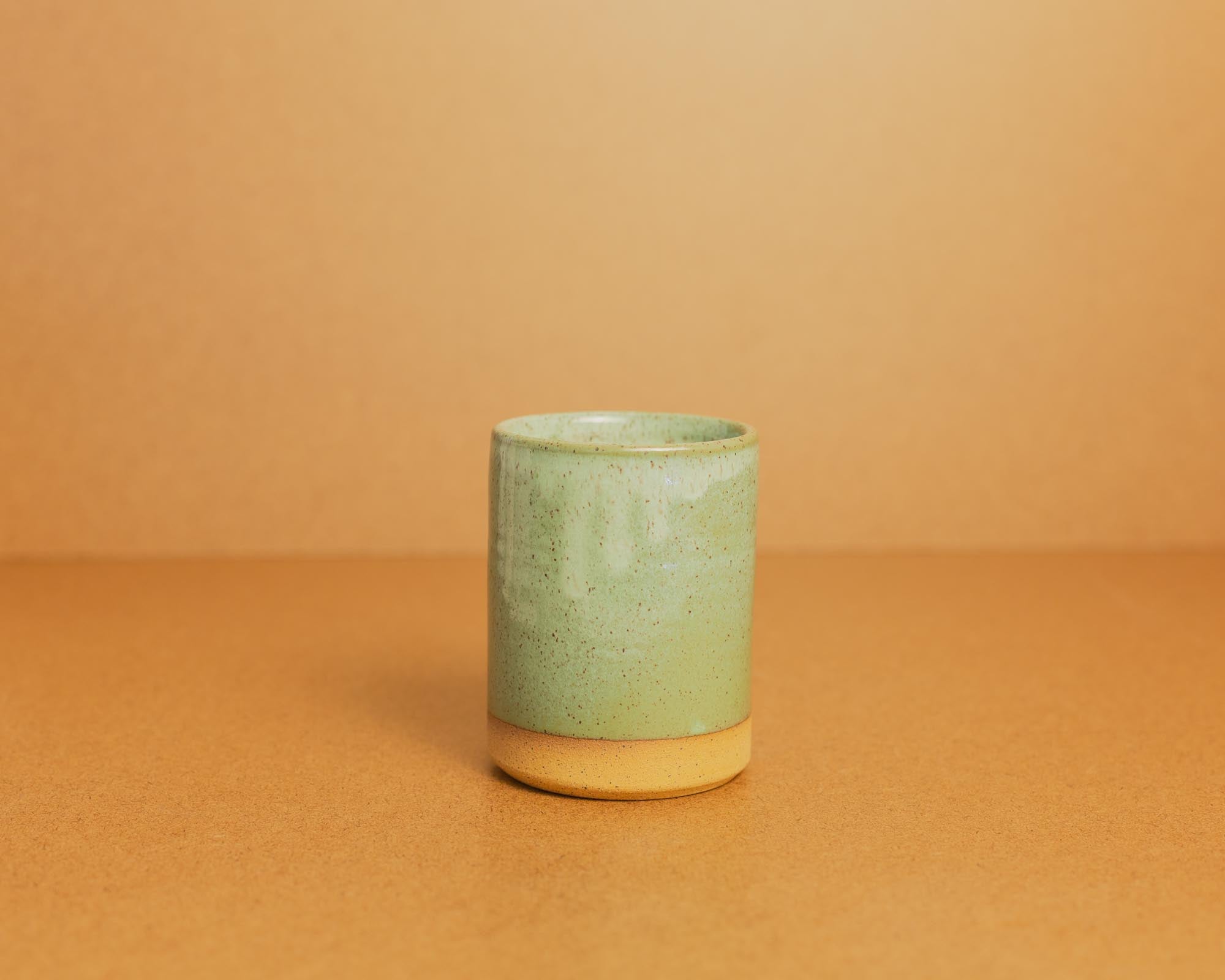 Green ceramic candle on a brown background