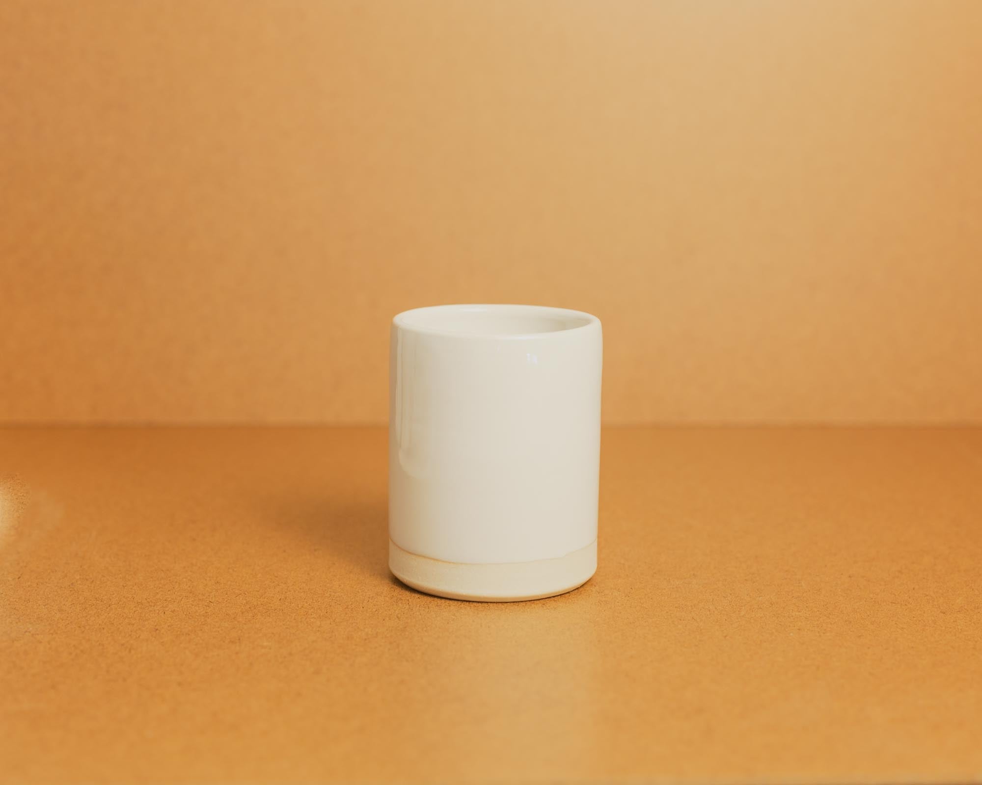 White ceramic candle on a brown background