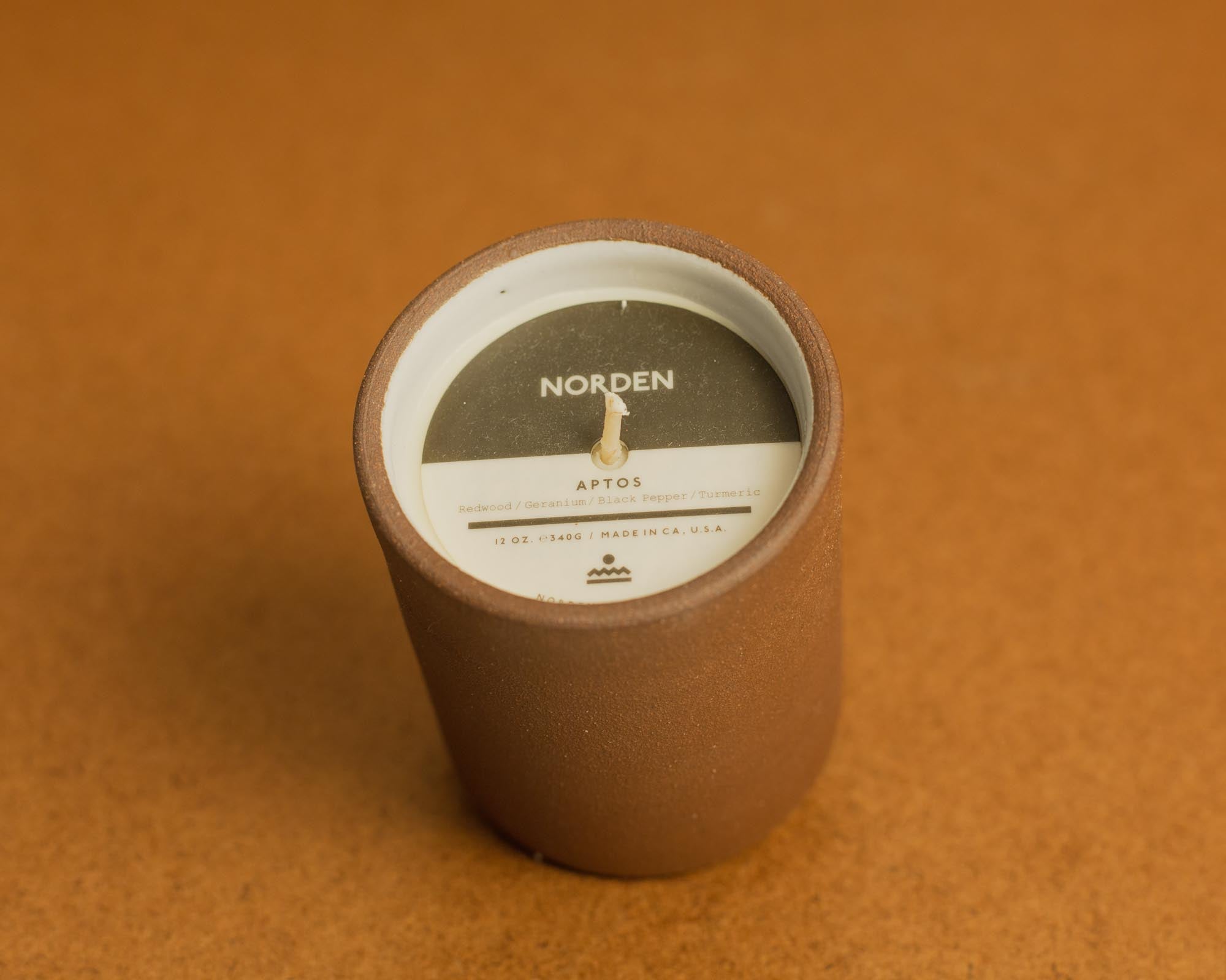 Brown ceramic candle with a label on a brown background