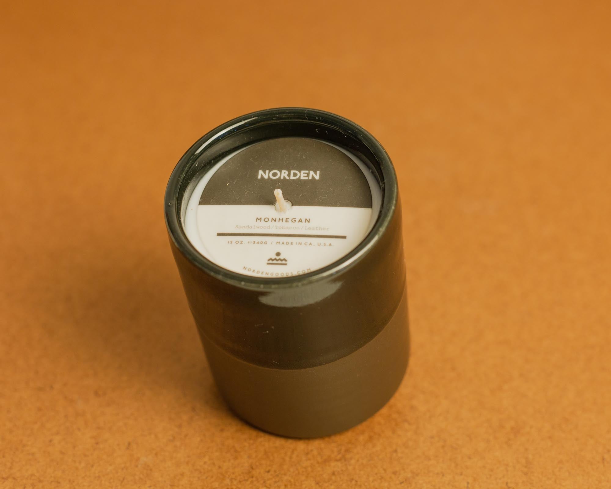 Black ceramic candle with a label on a brown background