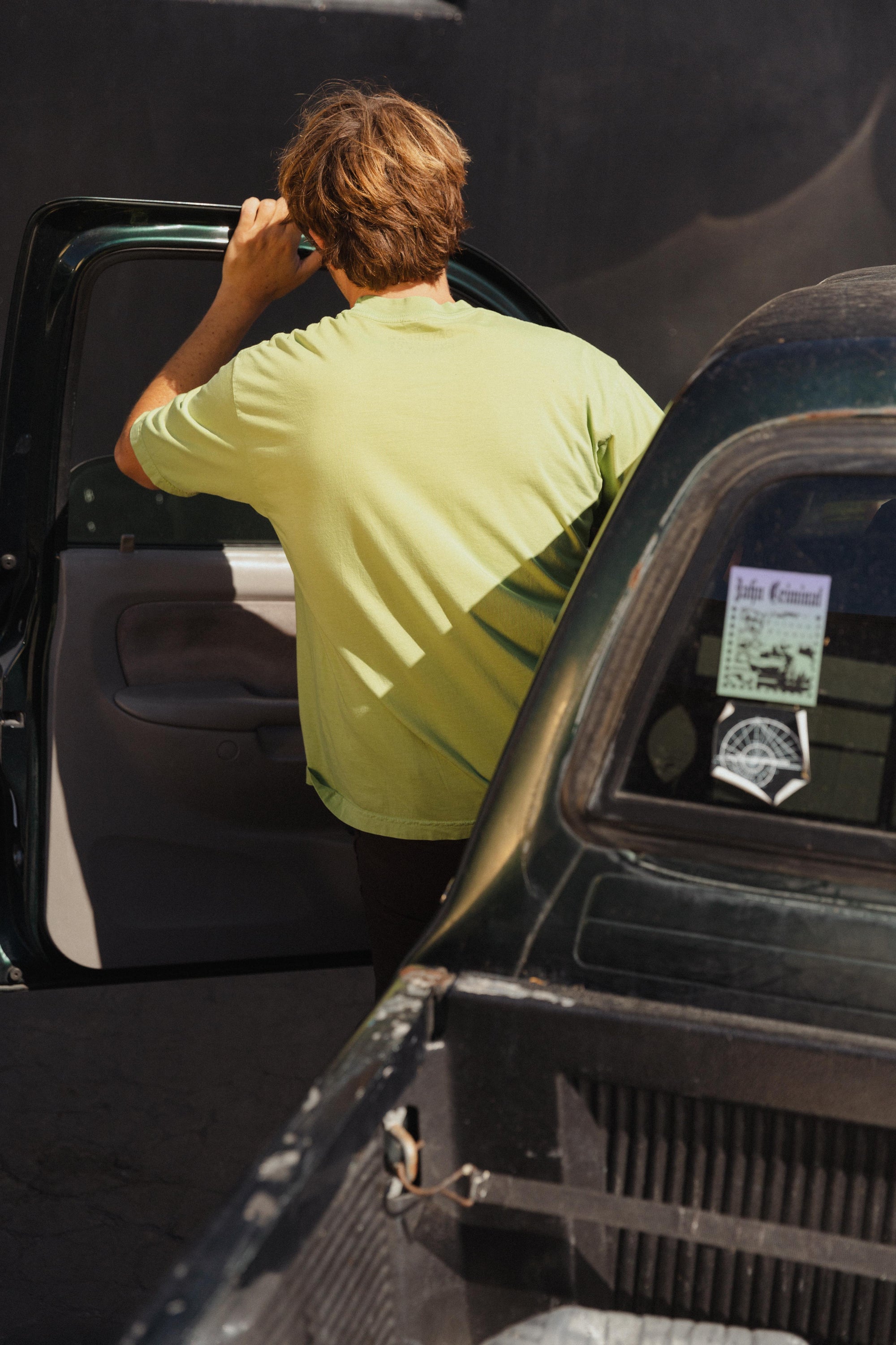 Person in a green shirt getting into an open car door