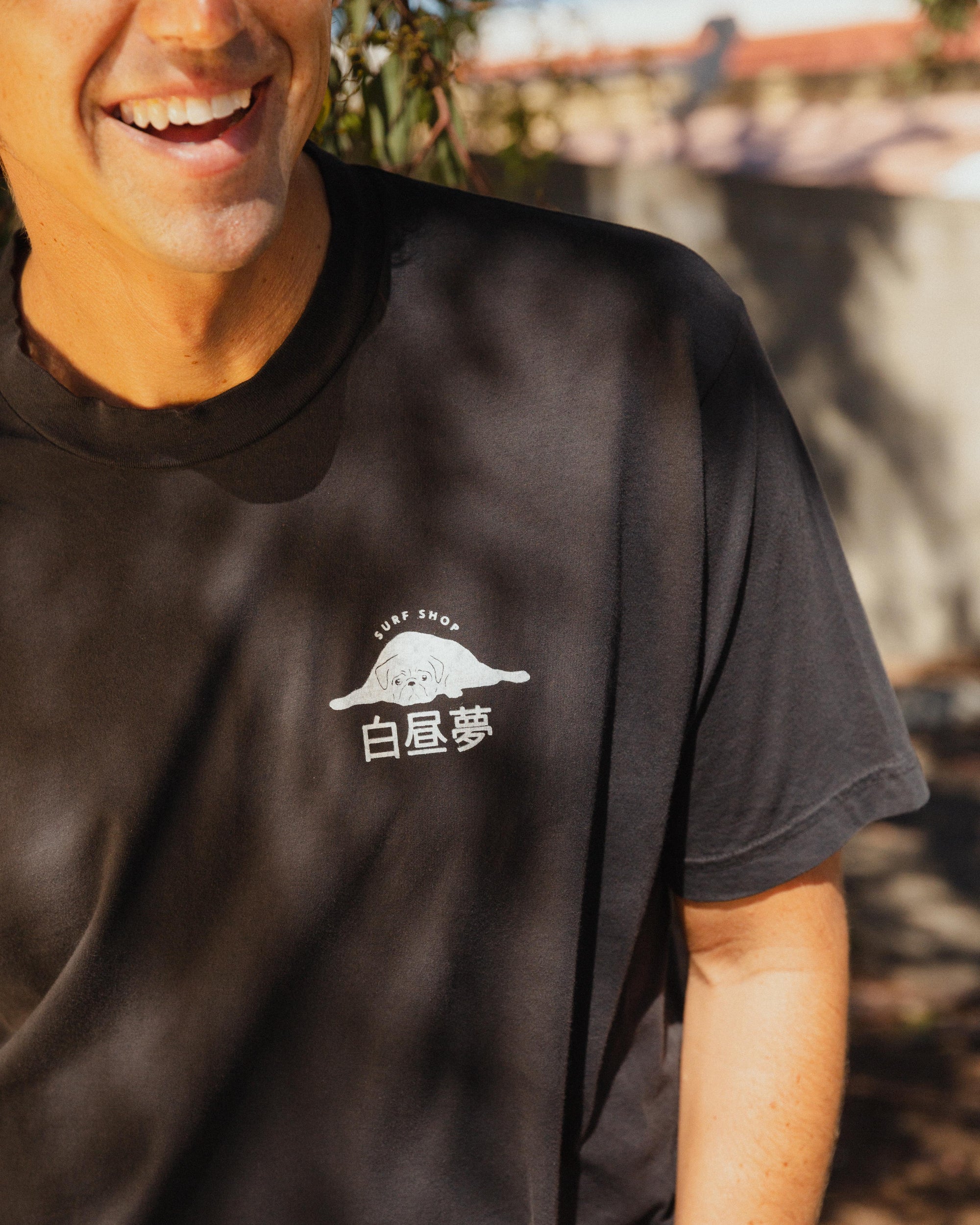 Person wearing a black t-shirt with a white Daydream Surf Shop logo and text