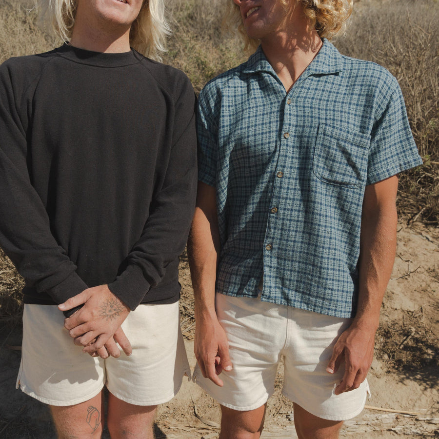 Two People wearing Mens Cotton Canvas Shorts in White and One Wearing Plaid Button-Up Shirt in Blue, Close-Up